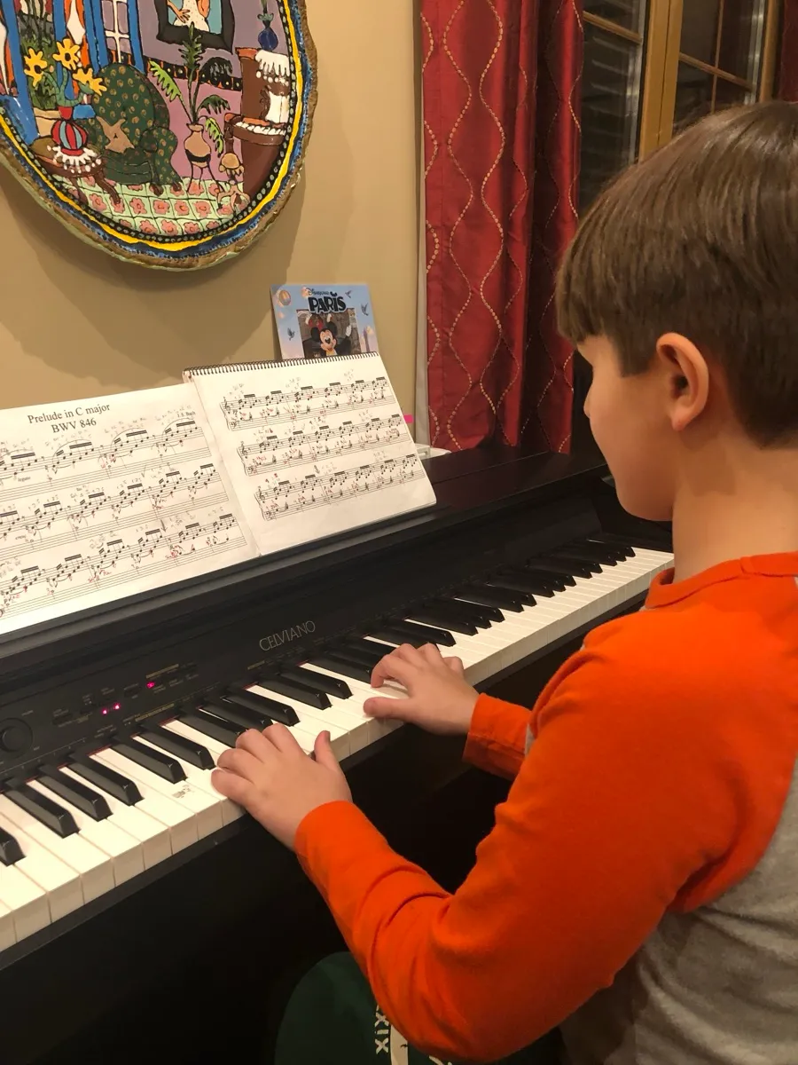 Niño tocando el Preludio en Do mayor de Bach en clase de piano