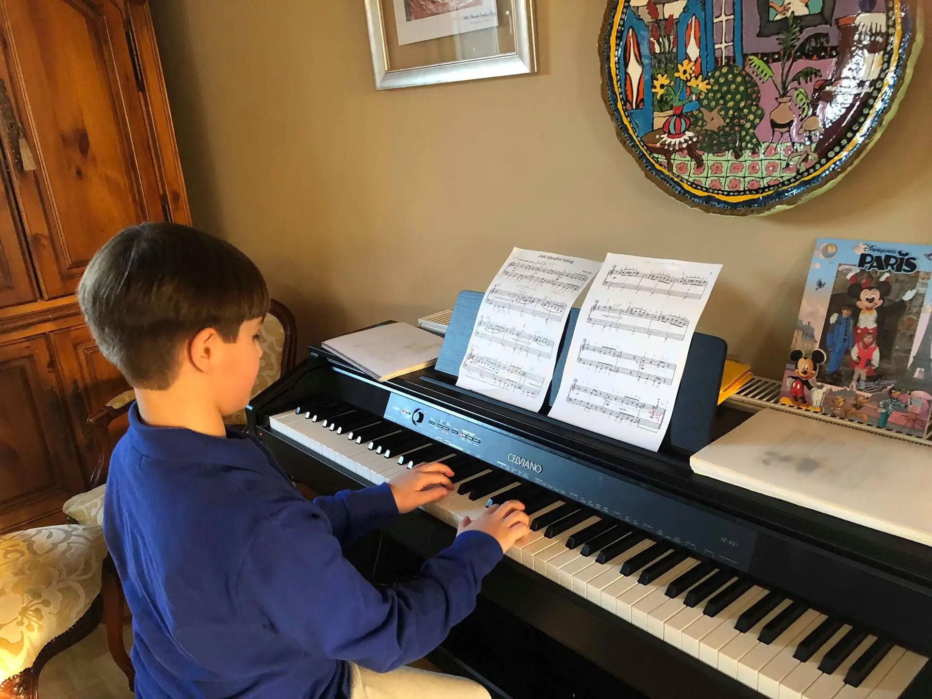 Alumno tocando el piano con partituras durante una clase de piano en Oviedo